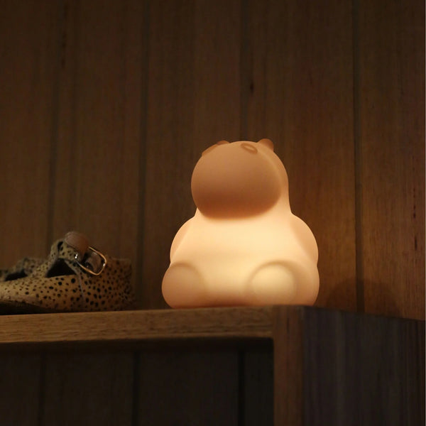 Hippo nightlight on shelf, lit up and glowing for kids that are scared of the dark.