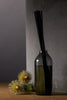 Ashley & Co home fragrance diffuser in smoky glass bottle with black reeds, styled with dried native florals against a dark concrete background.