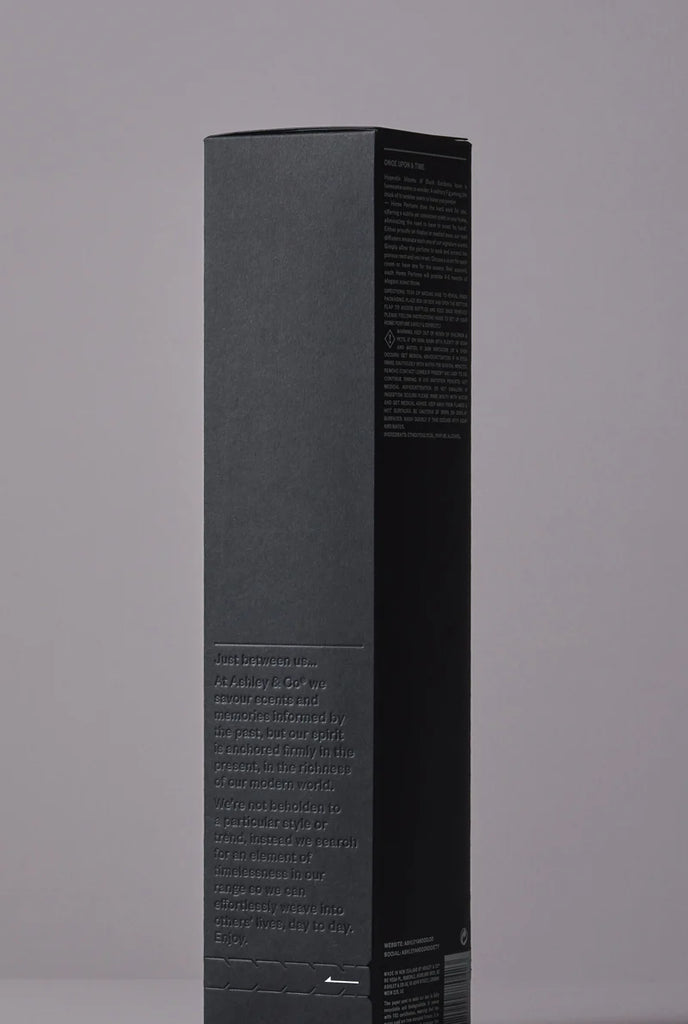Side view of Ashley & Co diffuser packaging in matte black with embossed brand story and product details on a neutral backdrop.