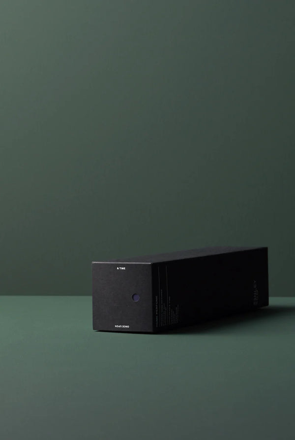 Ashley & Co diffuser box lying flat on a green surface with minimalist black packaging and subtle scent indicator dot.