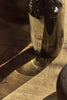 Ashley & Co black glass diffuser casting warm shadows on a wooden surface, luxury home fragrance with moody, natural lighting.