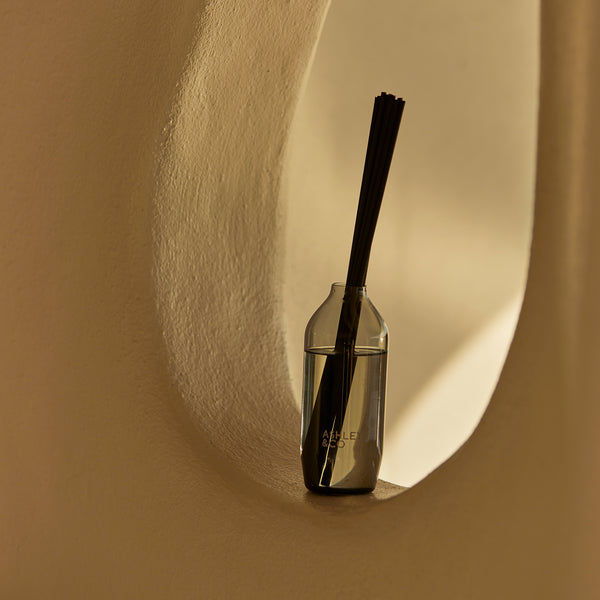Ashley & Co black reed diffuser displayed in a curved architectural nook, bathed in warm natural light for a serene and minimal interior styling.