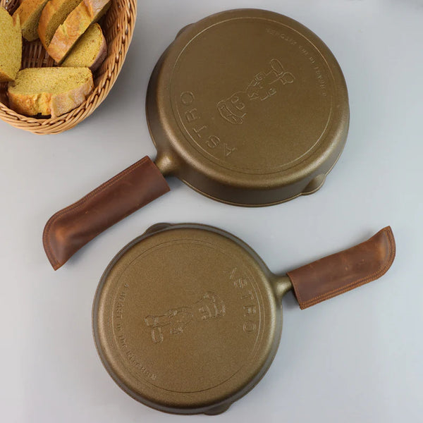 Two gold ASTRO cast iron skillets with leather handles cast iron pans