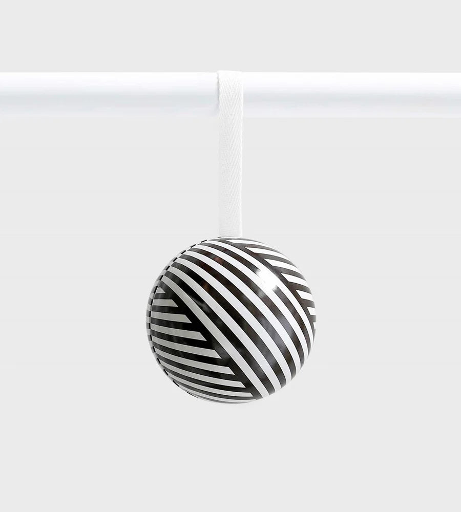 Black and white striped ceramic ornament with an optical illusion pattern, hanging from a white ribbon against a light grey background