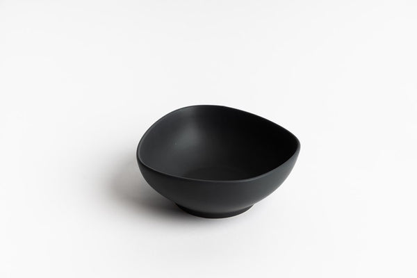Minimalist black ceramic bowl with an organic, curved shape, photographed on a white background – ideal for modern kitchen or dining styling.