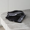 Pair of black and grey waffle tea towels with "Designstuff" label, folded on a marble bench.