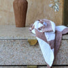 A soft, textured tea towel in brown and white stripes draped over a stone drawer unit, with a tall, earthy-toned vase in the background.