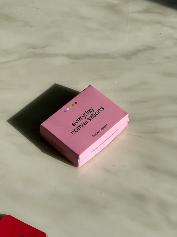 Pink box of “Everyday Conversations” card game resting on a marble surface, designed to spark deeper daily dialogue