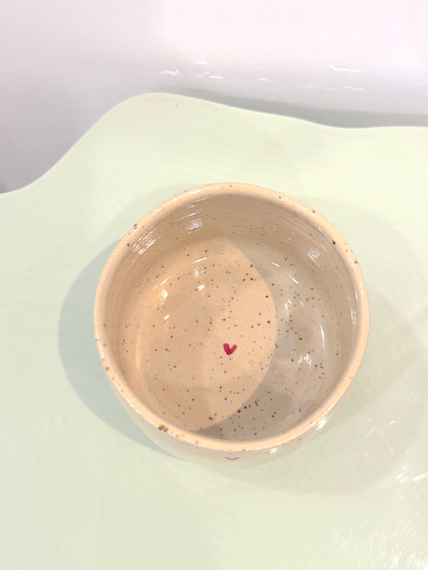 Speckled ceramic mug with a red heart on a light green background