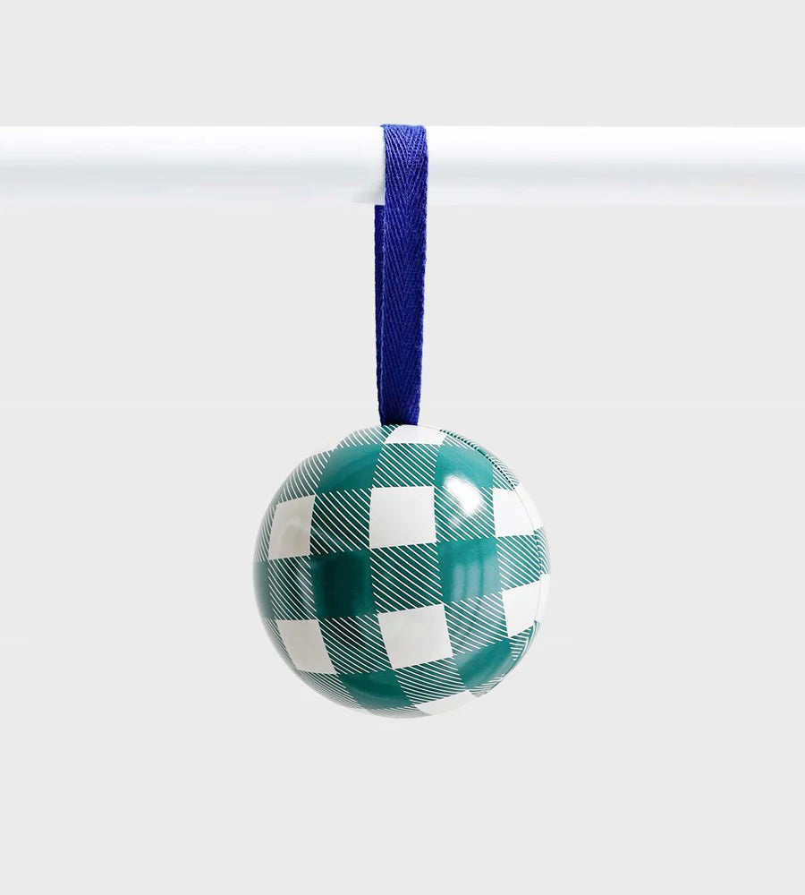 Green and white checkered ceramic ornament with fine diagonal detailing, hanging from a royal blue ribbon against a light grey background