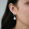 Sterling silver hoop earring with a single freshwater pearl drop, shown worn on ear.