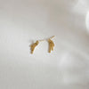 Gold chain fringe stud earrings displayed on a soft white fabric background, showcasing their delicate and elegant design.