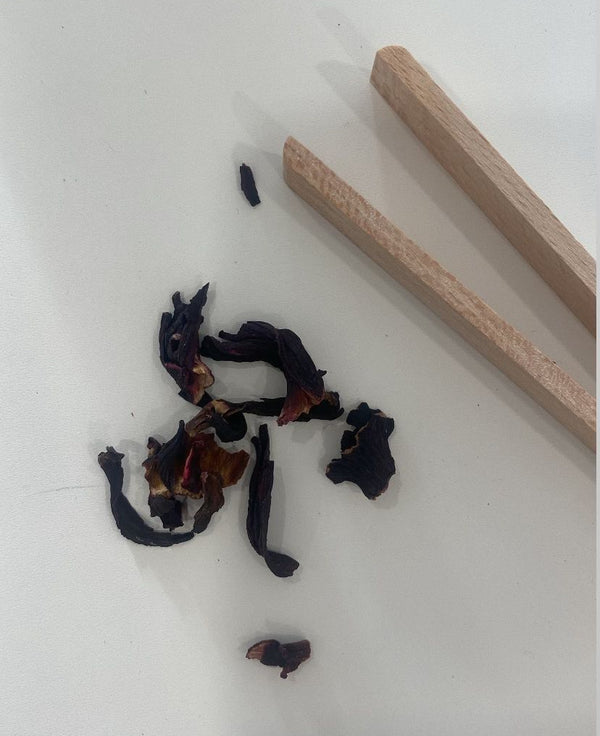 Loose leaf tea blend with dried fruit and petals next to wooden blending sticks – a DIY tea mixing flat lay.
