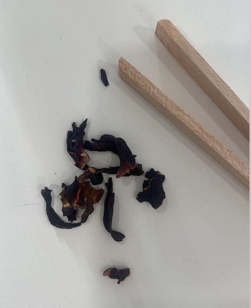 Loose leaf tea blend with dried fruit and petals next to wooden blending sticks – a DIY tea mixing flat lay.