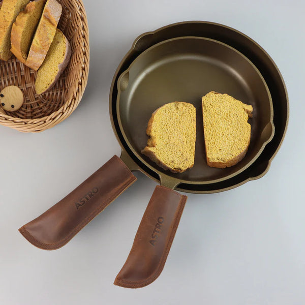 two gold skillets with leather handle heat protection