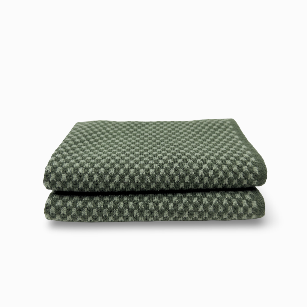 A folded green and white checkered fabric item, likely a blanket or towel, shown on a clean white background.