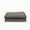 A folded cloth featuring a dark brown and light beige checkerboard pattern, set against a plain white background.