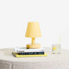 Yellow lamp on a stack of books with a glass of lemonade on a light gray surface.