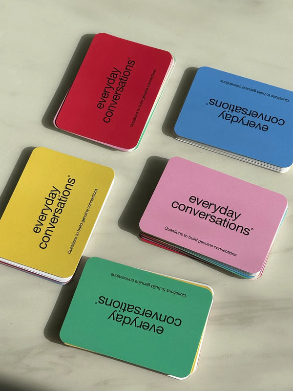 Assorted “Everyday Conversations” cards in colourful decks spread out on a marble surface, designed to spark meaningful dialogue