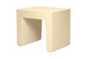 A modern, minimalist side table with a thick, blocky rectangular base in a warm cream or beige finish, isolated on a white background.
