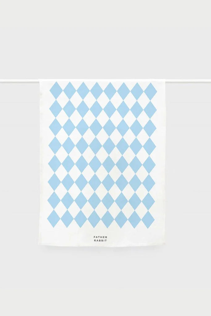 Flat lay of a white tea towel featuring a light blue harlequin pattern and "Father Rabbit" branding at the base.