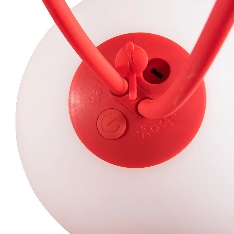 Close-up of a red plastic lamp base with two red curved arms extending upward, set against a white background.