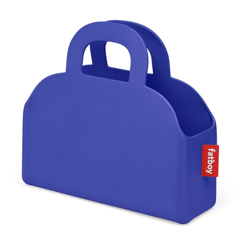 A royal blue silicone baby or food or bottle carrier shaped like a handbag, featuring integrated handles and a small red fabric brand tag on the side with the white text 'fatboy'.