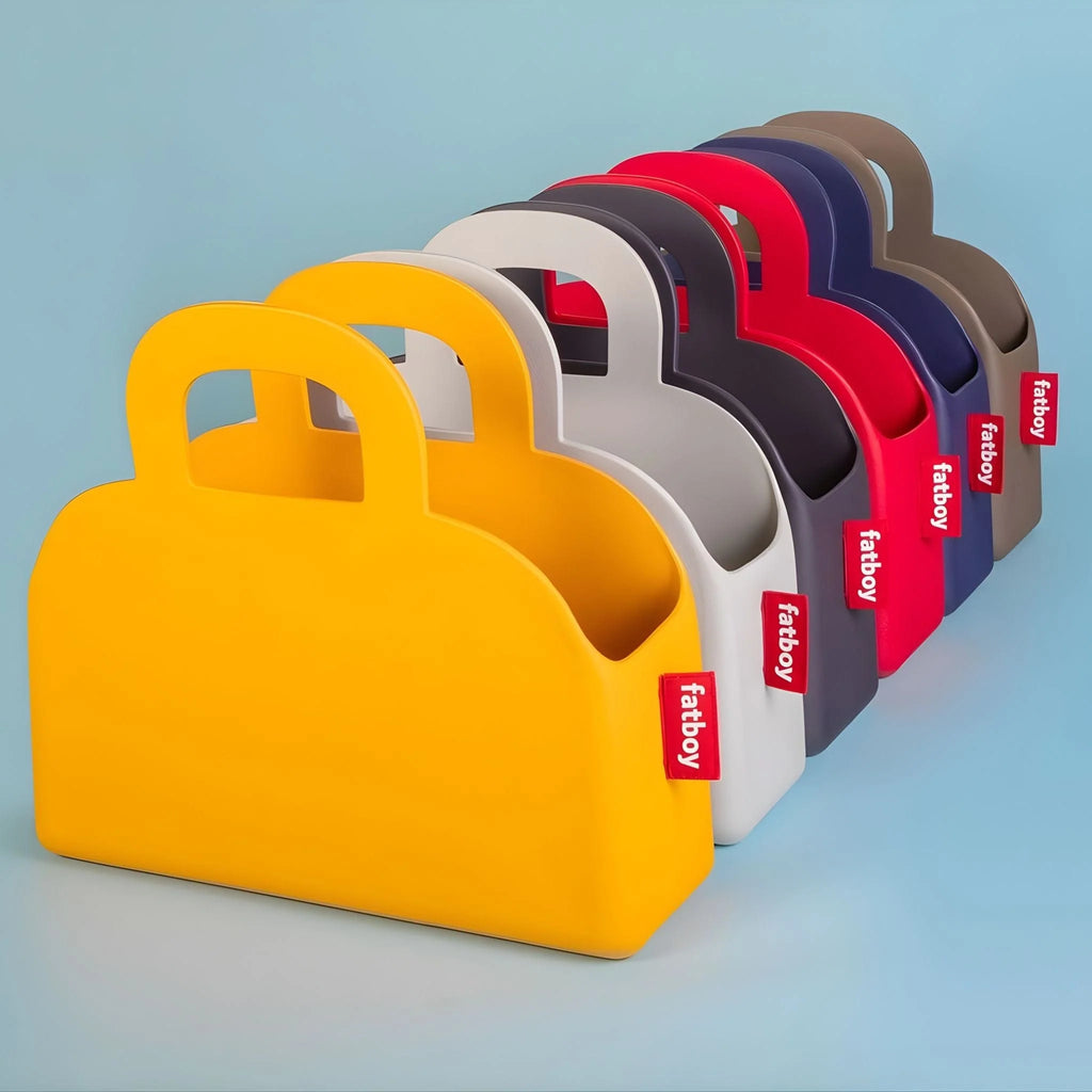 A set of six Fabboby handbag-shaped bag in assorted colours, arranged in a diagonal row on a light blue background.