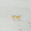 Pair of gold lily earrings with pearl centers on a light grey background