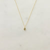 Gold necklace with a heart pendant and small diamond on a light grey  background