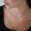 Model wearing a delicate silver necklace with a heart pendant with a tiny diamond in centre of heart